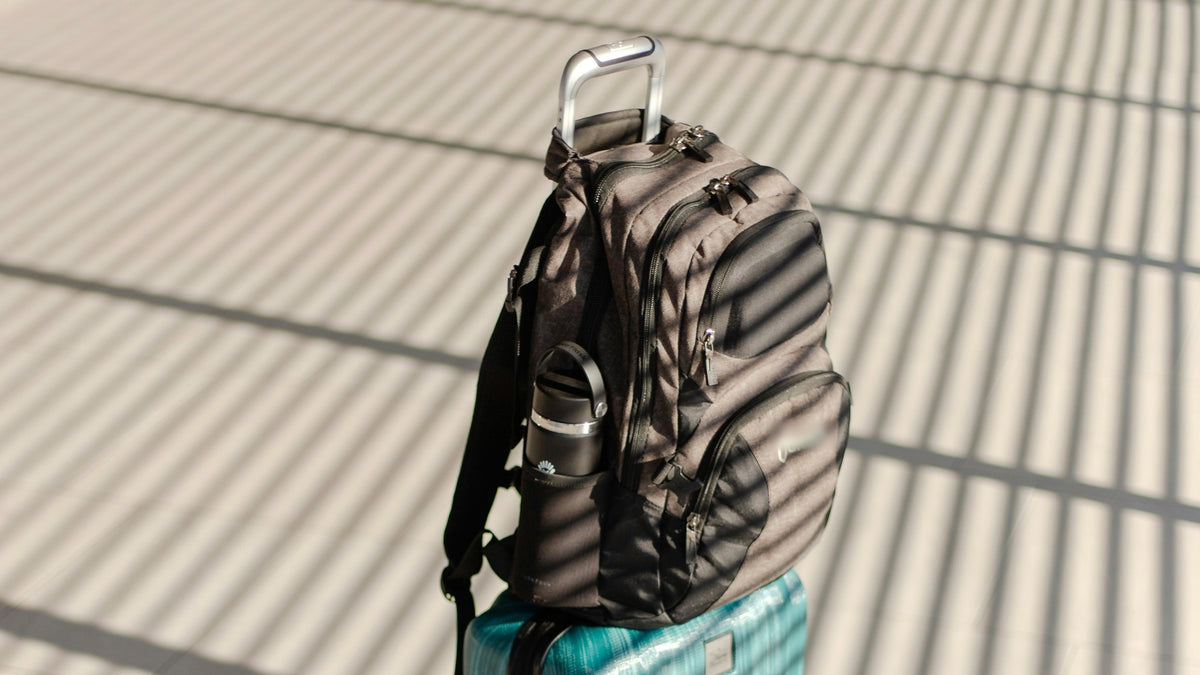 Mochila de viaje apoyada sobre una maleta de cabina en una terminal